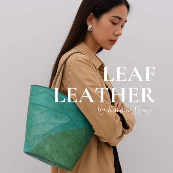 Woman carrying a green leaf leather handbag by Karuna Dawn, wearing a tan jacket against a plain background.
